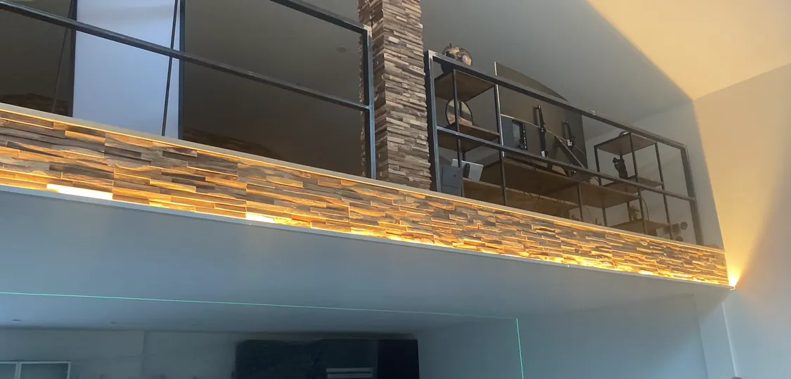 Indirekte warmweiße LED-Beleuchtung hinter der Holzverkleidung einer Galerie im Wohnbereich