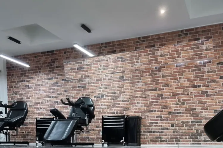 Studiofläche mit linearen LED-Deckenleuchten und Downlights vor einer Klinkerwand