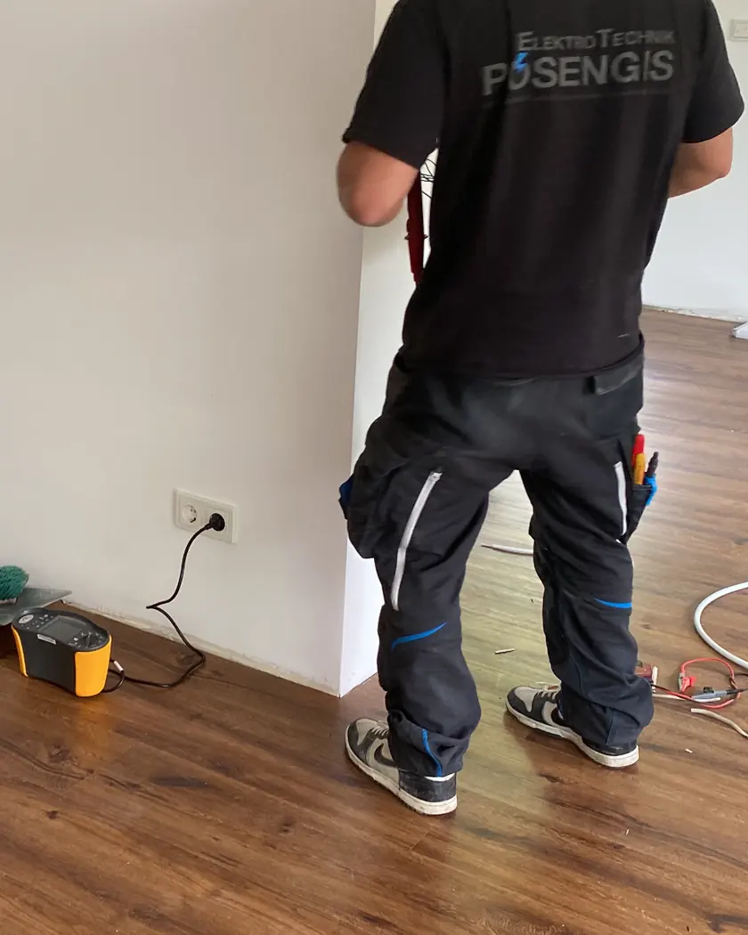 Mitarbeiter von ElektroTechnik Posengis bei der Prüfung einer Wohnung: Ein Installationstester ist an eine Wandsteckdose angeschlossen