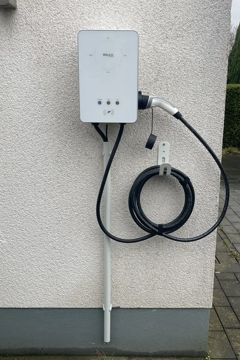 Fertig installierte SolaX-Wallbox an einer Hauswand mit Zuleitung im Schutzrohr und Ladekabel am Wandhalter – Wallbox-Installation von ElektroTechnik Posengis
