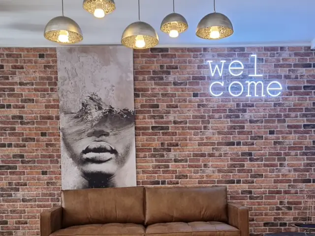 Pendelleuchten über einer Lounge vor Ziegelwand mit Neon-Schriftzug