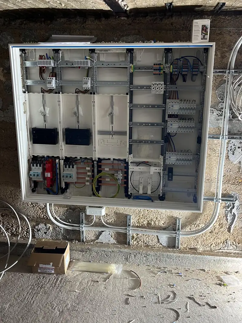 Großer Zählerschrank im Rohbau-Keller während der Montage mit drei Zählerplätzen, Hauptleitungsschutz, Überspannungsschutz, APZ-Feld und Verteilerfeld